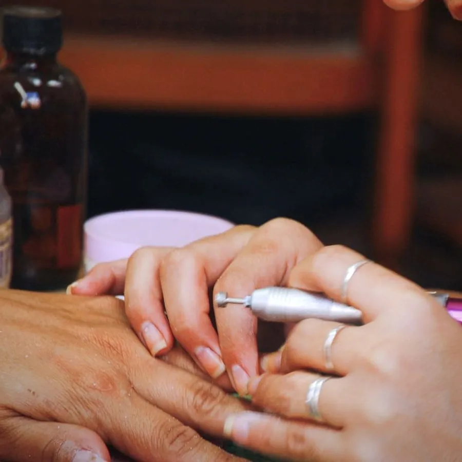 Manicure in corso al tavolo di lavoro, con boccetta e strumenti